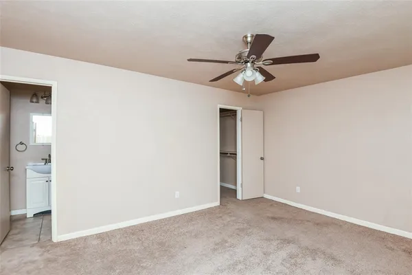 an empty room with windows and ceiling fan