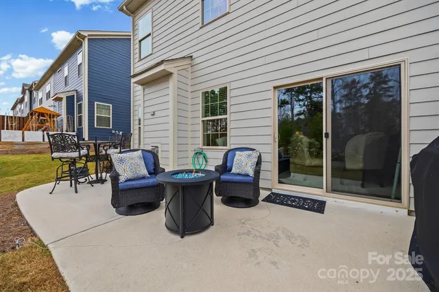 a view of a patio with table and chairs potted plants and floor to ceiling window