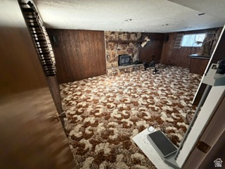 588 North 4500 West West Point, UT 84015 - Photo 26 of 61 Spacious room featuring a stone-clad fireplace and hearth, wood paneling, patterned carpet, and a window with blinds