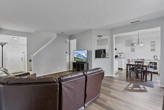 a living room with furniture a flat screen tv and kitchen view