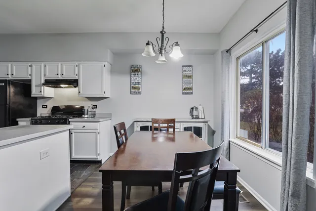 a kitchen with kitchen island granite countertop a dining table chairs and white cabinets