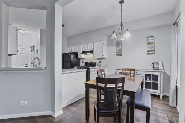 a view of a dining room and livingroom with furniture wooden floor a chandelier