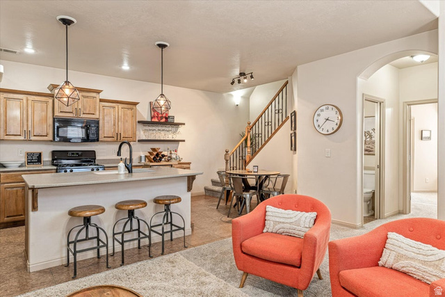 345 North 2450th Street East, Unit 152 St. George, UT 84790 - Photo 13 of 40 Kitchen with arched walkways, black appliances, a kitchen bar, a kitchen island with sink, and open shelves