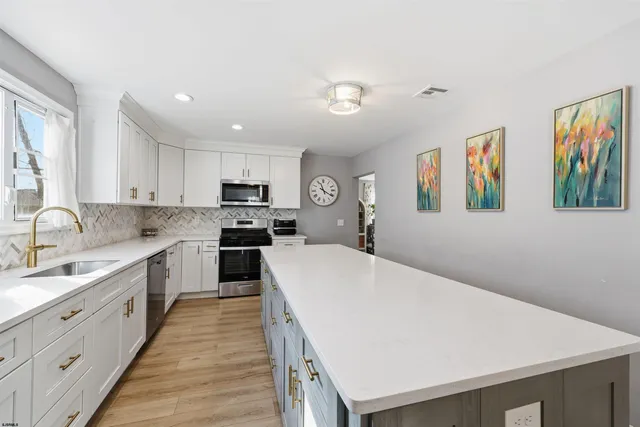 a large kitchen with stainless steel appliances granite countertop a sink dishwasher a stove and a refrigerator with wooden floor