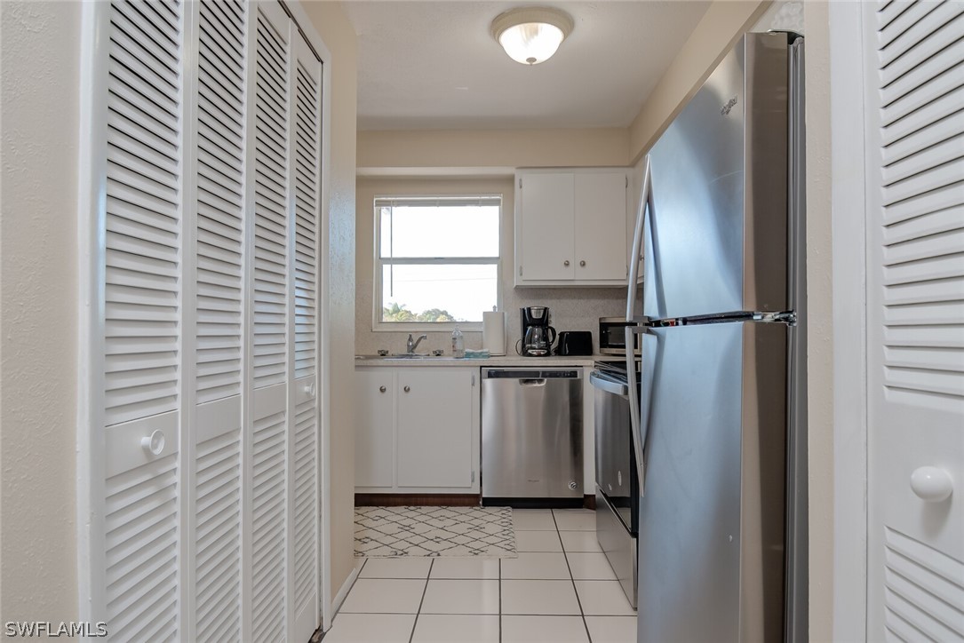 6777 Winkler Road, Unit 237 Fort Myers, FL 33919 - Photo 7 of 23 a kitchen with a refrigerator and white cabinets