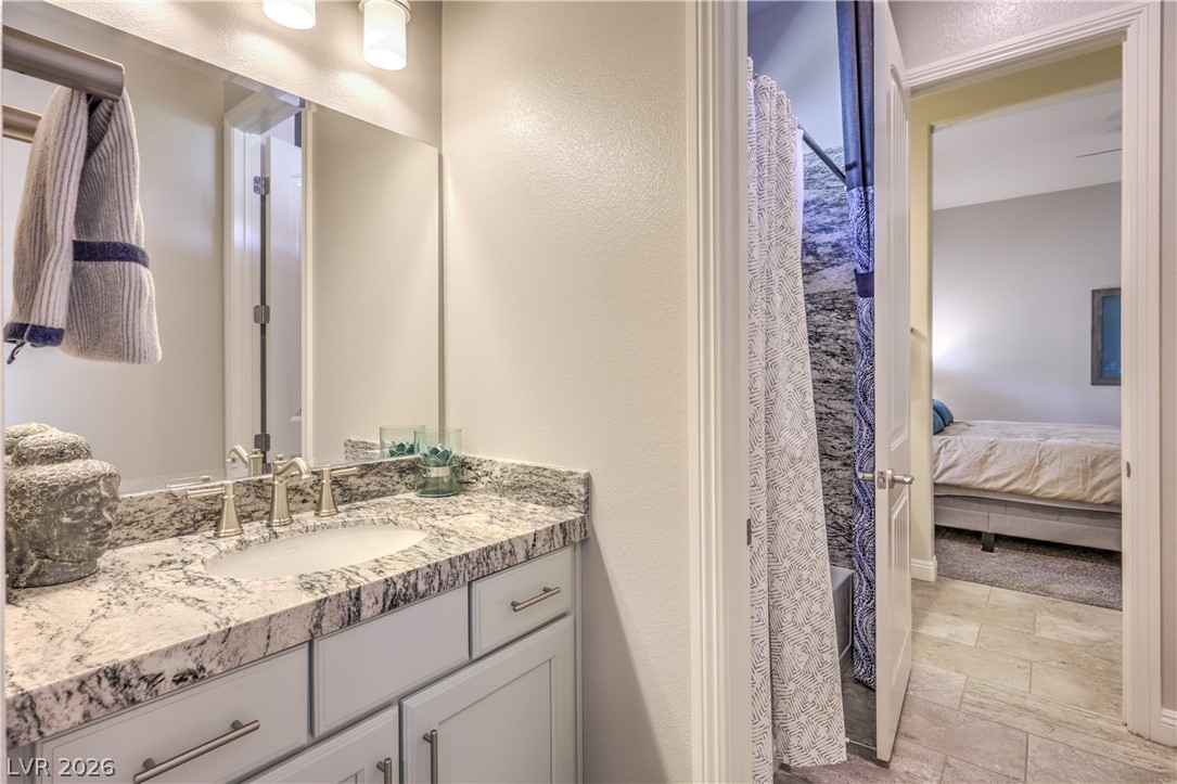 7119 Arabian Ridge Street Las Vegas, NV 89131 - Photo 32 of 73 Marble vanity with modern fixtures and tile flooring leading into a comfortable adjacent sleeping area.