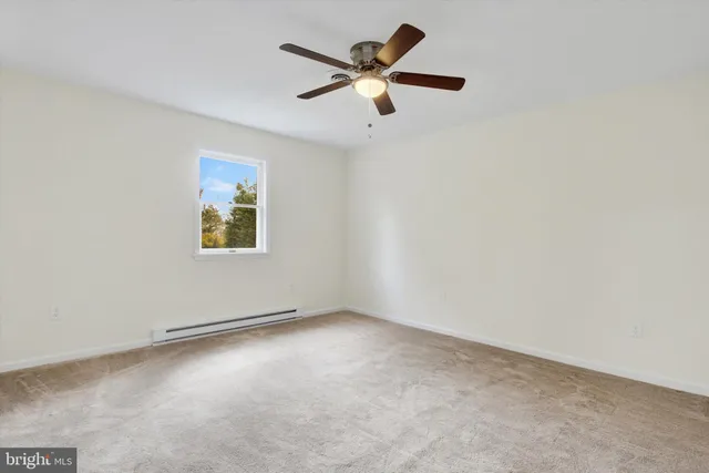 an empty room with a window and a fan