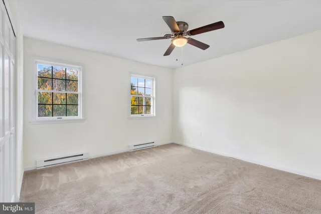 an empty room with windows and fan