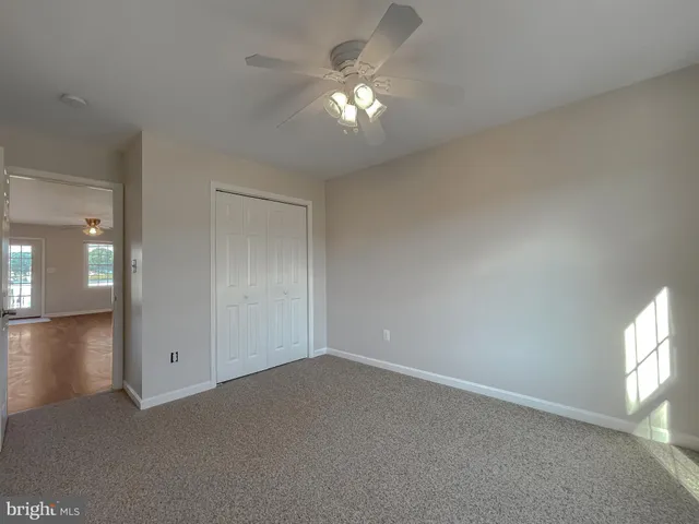 an empty room with a window and chandelier fan
