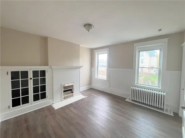 an empty room with windows and a fireplace