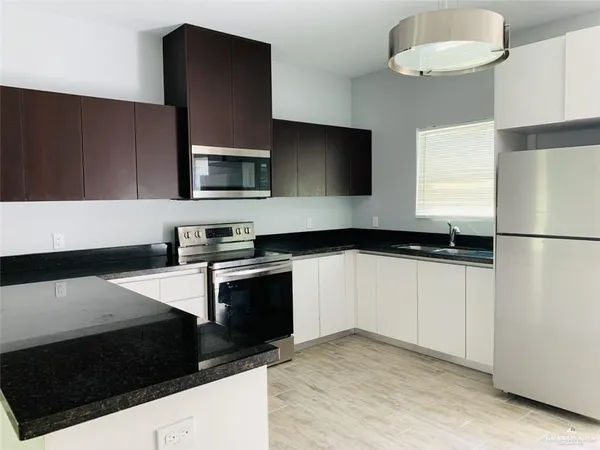 a kitchen with granite countertop a refrigerator stove and microwave