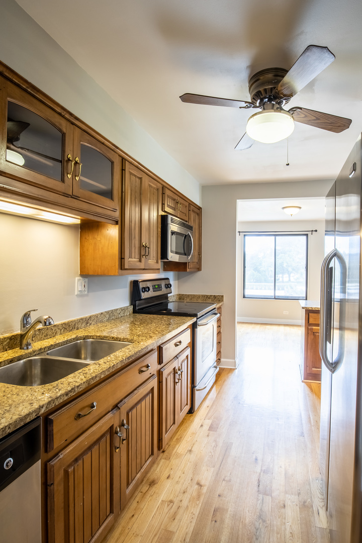 1515 East Central Road, Unit 258A Arlington Heights, IL 60005 - Photo 2 of 5 a kitchen with stainless steel appliances a sink dishwasher a stove a refrigerator with wooden floor and cabinets