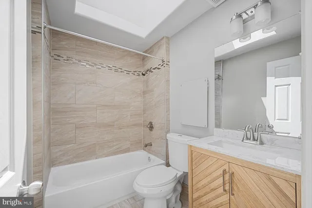 a bathroom with a granite countertop toilet a sink and a bathtub