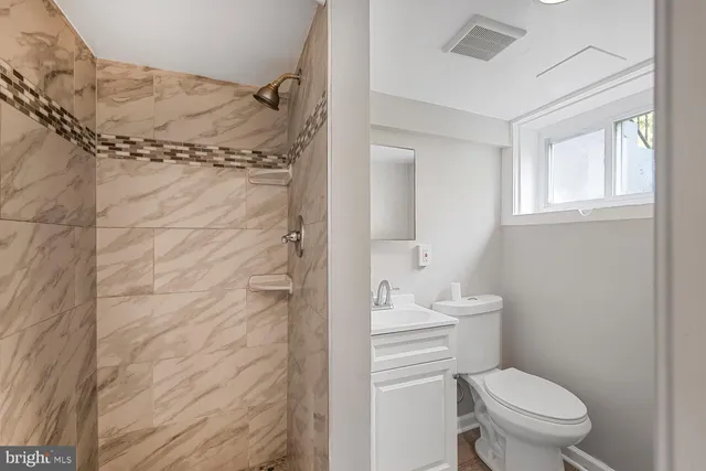a bathroom with a granite countertop toilet a sink and a shower