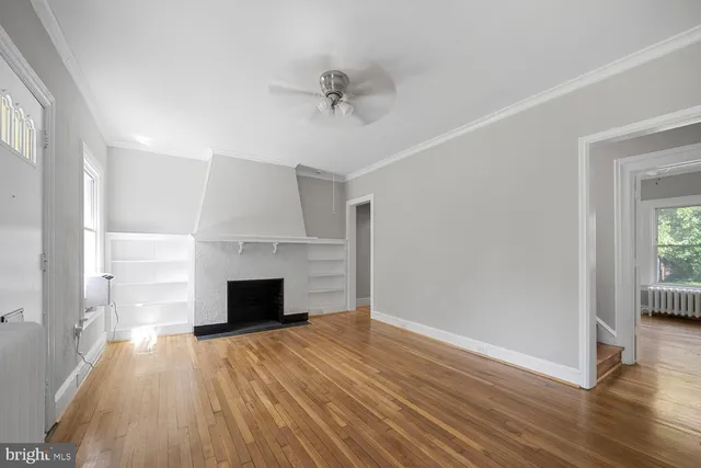 an empty room with wooden floor fireplace and windows