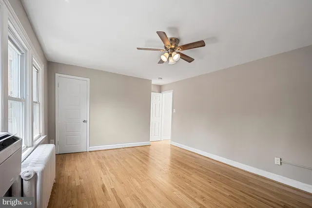 a view of empty room with wooden floor and fan