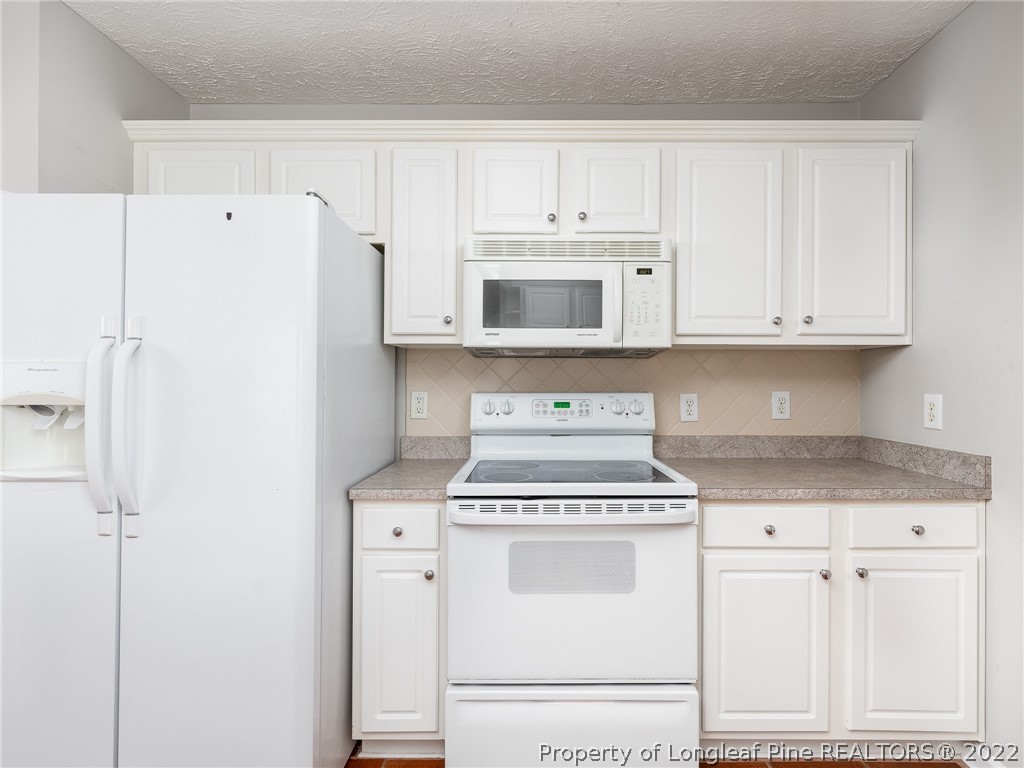 5716 Spreading Branch Road Hope Mills, NC 28348 - Photo 19 of 37 a kitchen with granite countertop white cabinets and white appliances