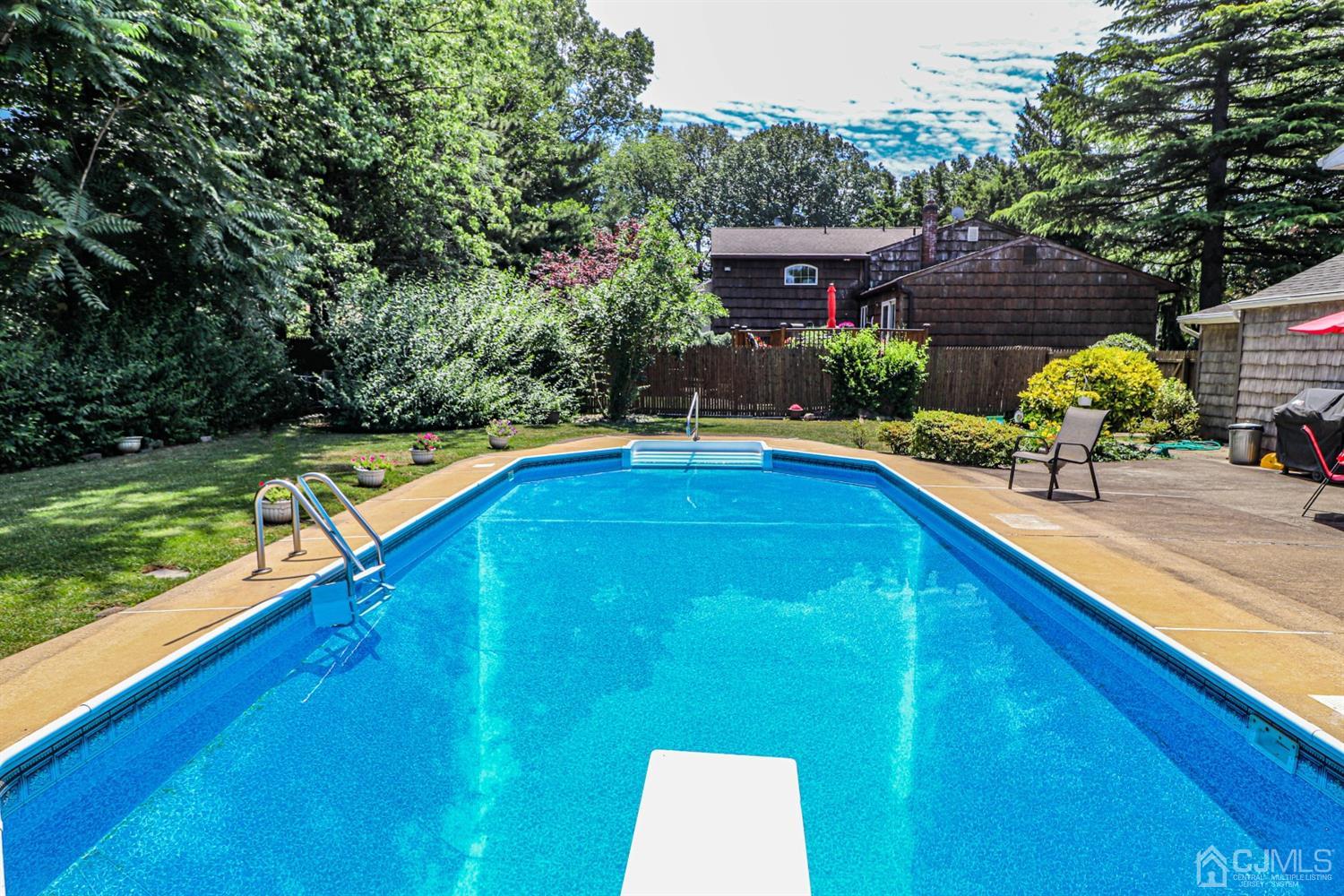 32 Monaghan Road Edison, NJ 08817 - Photo 32 of 35 a view of a swimming pool with lawn chairs plants and large trees