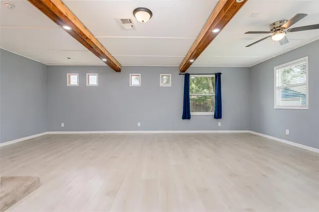 an empty room with windows and ceiling fan