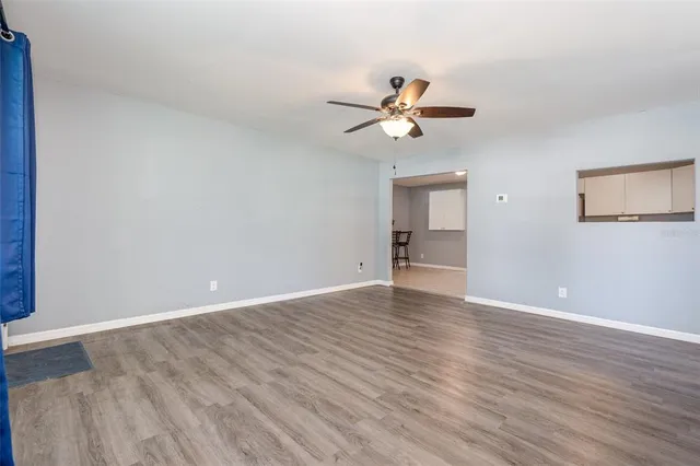 a view of empty room with wooden floor and ceiling fan