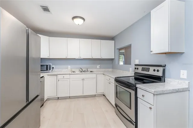 a kitchen with granite countertop white cabinets sink and stainless steel appliances