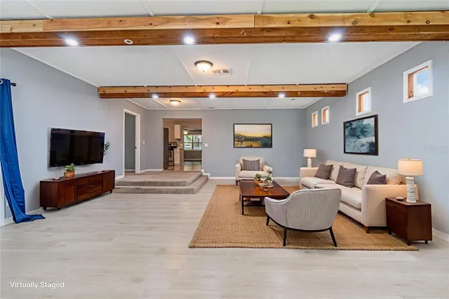 a living room with furniture a flat screen tv and kitchen view