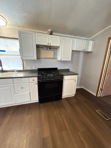 a kitchen with stainless steel appliances a stove a sink and white cabinets