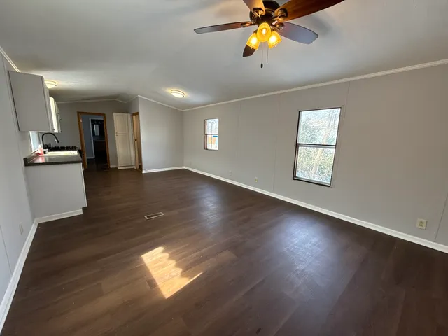 a view of an empty room with window and wooden floor