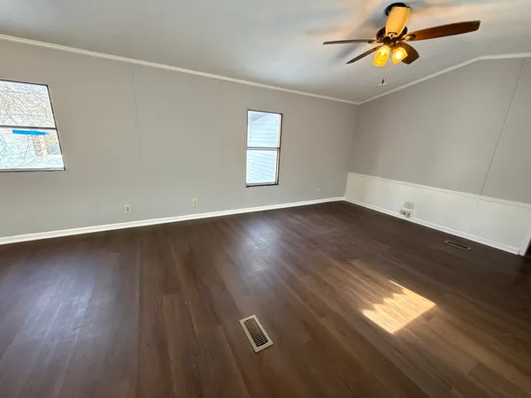 a view of an empty room with wooden floor and window