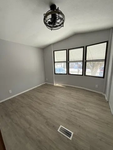 an empty room with windows and ceiling fan