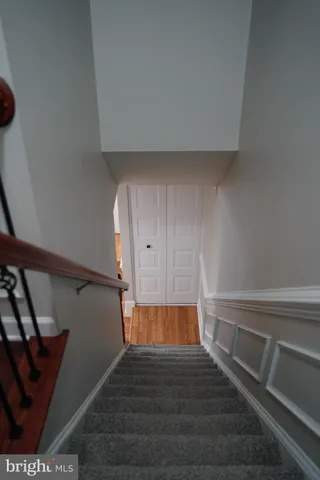 a view of stairs and an empty room with wooden floor