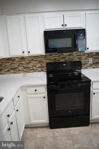 a kitchen with granite countertop white cabinets and stainless steel appliances