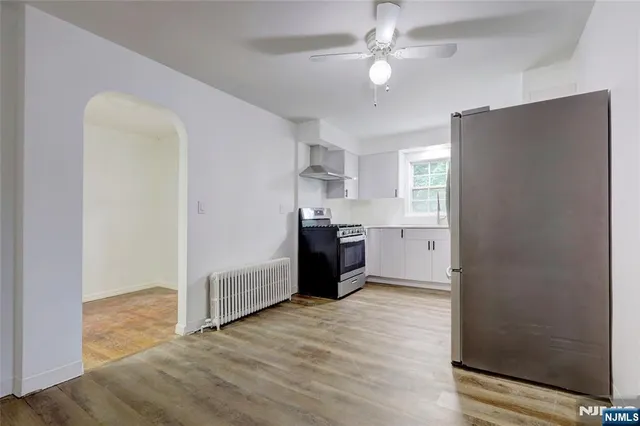 a view of a kitchen with wooden cabinet and a refrigerator a ceiling fan