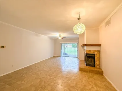 an empty room with a fireplace and chandelier