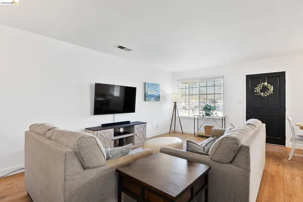 a kitchen with stainless steel appliances granite countertop a stove a sink dishwasher a refrigerator and white cabinets with wooden floor