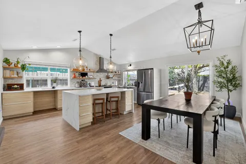 a kitchen with a table chairs a sink dishwasher window and cabinets
