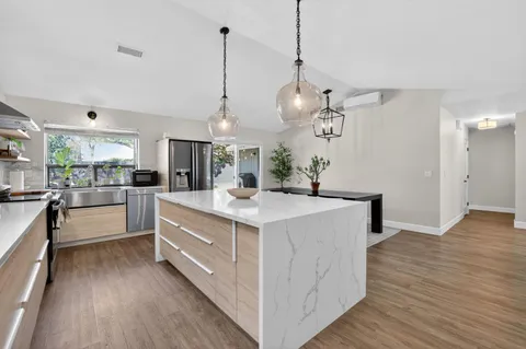 a kitchen with kitchen island a island in the center and white cabinets
