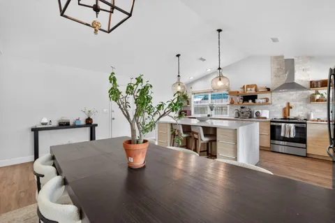 a open kitchen with stainless steel appliances granite countertop a stove a sink a dining table and chairs