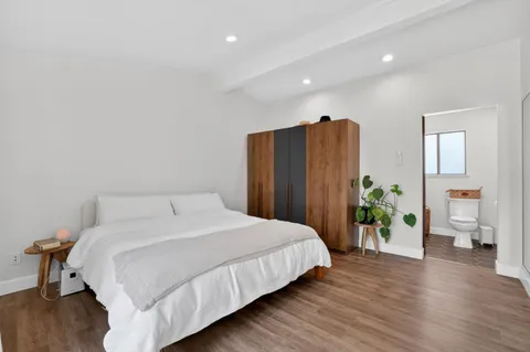 a bedroom with a large bed and wooden floor