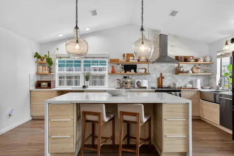 a kitchen with kitchen island granite countertop a sink stove and wooden floor
