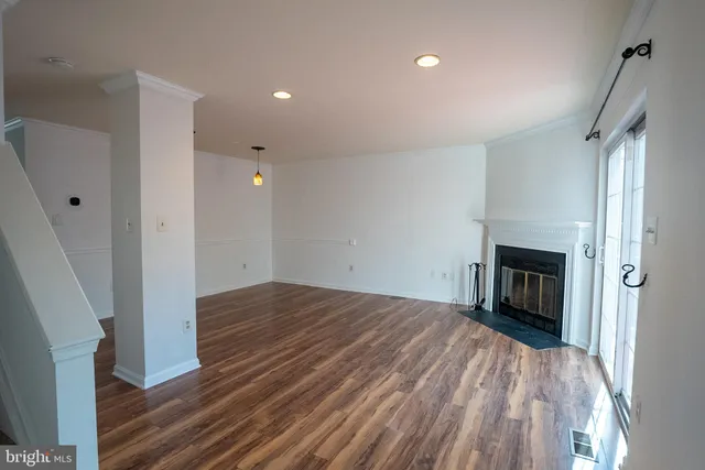 a view of empty room with wooden floor and fireplace
