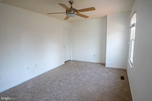 an empty room with a fan and a window