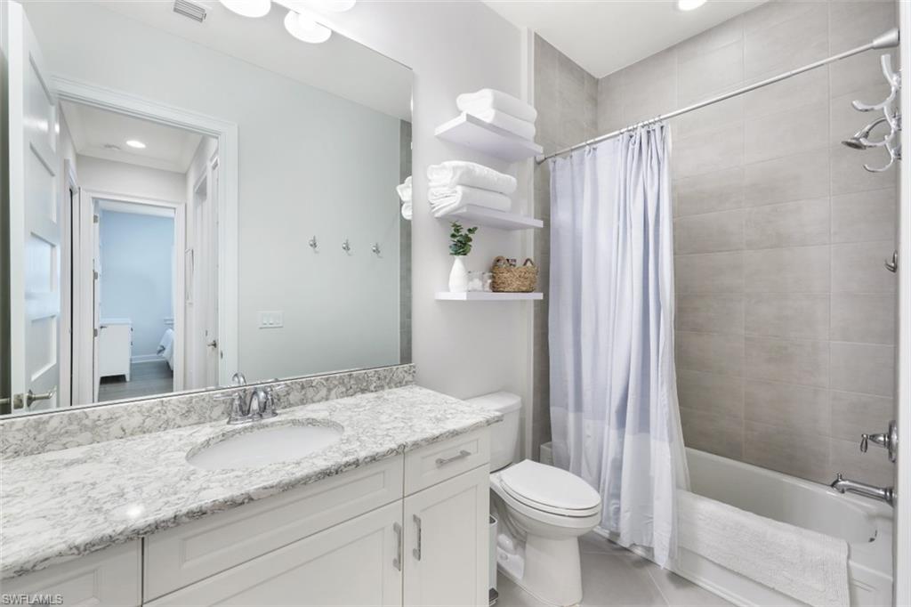 6295 Arriba Avenue Naples, FL 34113 - Photo 19 of 34 a bathroom with a granite countertop sink toilet and shower