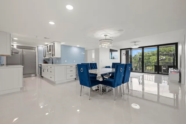 a living room with stainless steel appliances furniture a large window and a kitchen view