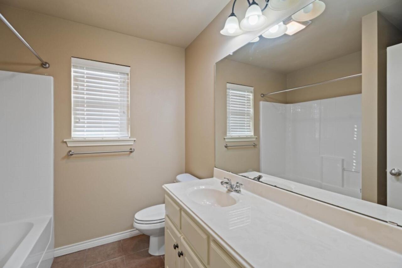 6112 101st Street Lubbock, TX 79424 - Photo 15 of 20 a bathroom with a sink a toilet and a mirror