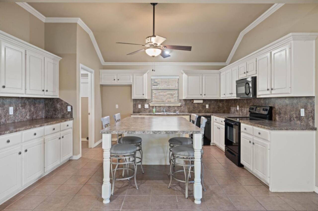 6112 101st Street Lubbock, TX 79424 - Photo 5 of 20 a kitchen with stainless steel appliances granite countertop a stove top oven a refrigerator a sink with a dining table and chairs