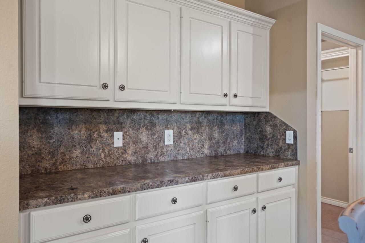 6112 101st Street Lubbock, TX 79424 - Photo 7 of 20 a kitchen with white cabinets and a granite counter top