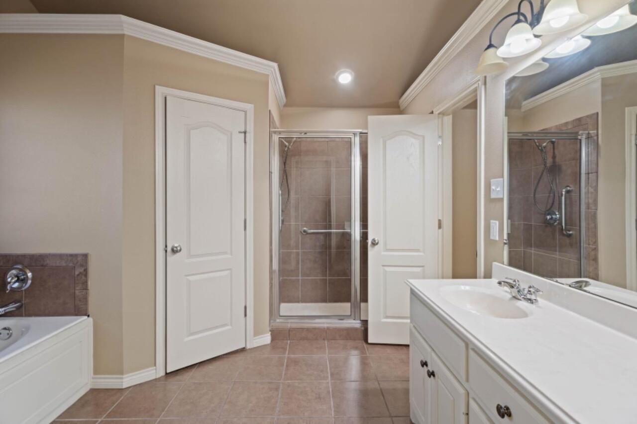 6112 101st Street Lubbock, TX 79424 - Photo 10 of 20 a bathroom with a double vanity sink mirror and shower