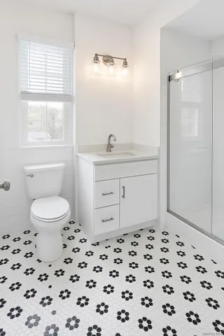 a bathroom with a sink a toilet a window and shower