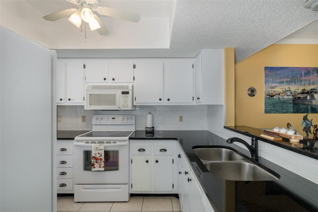 8210 Aquila Street, Unit 213 Port Richey, FL 34668 - Photo 16 of 48 a kitchen with kitchen island a sink a stove and white cabinets